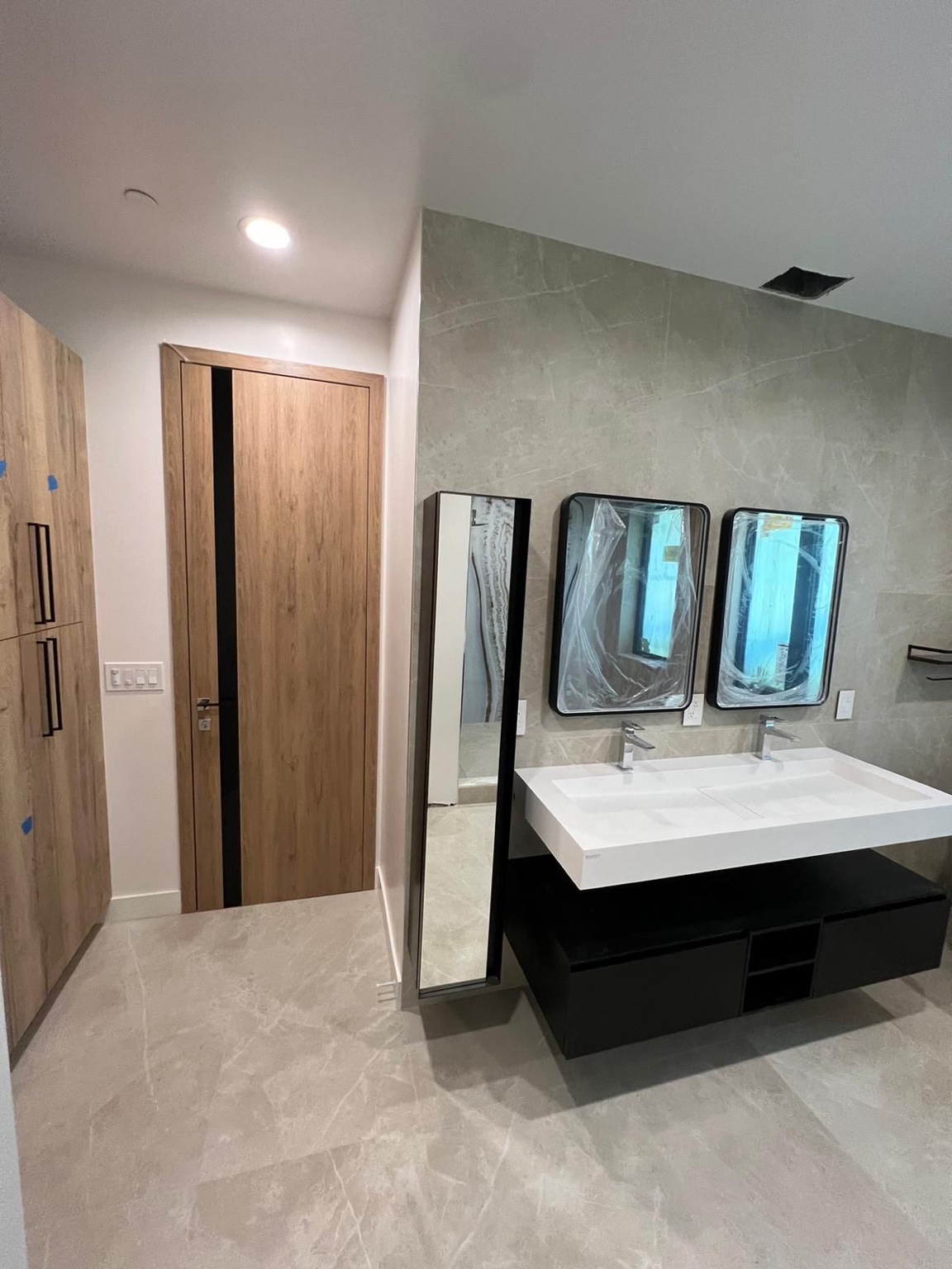 Double vanity in progress with black cabinetry, white sinks and wall tile