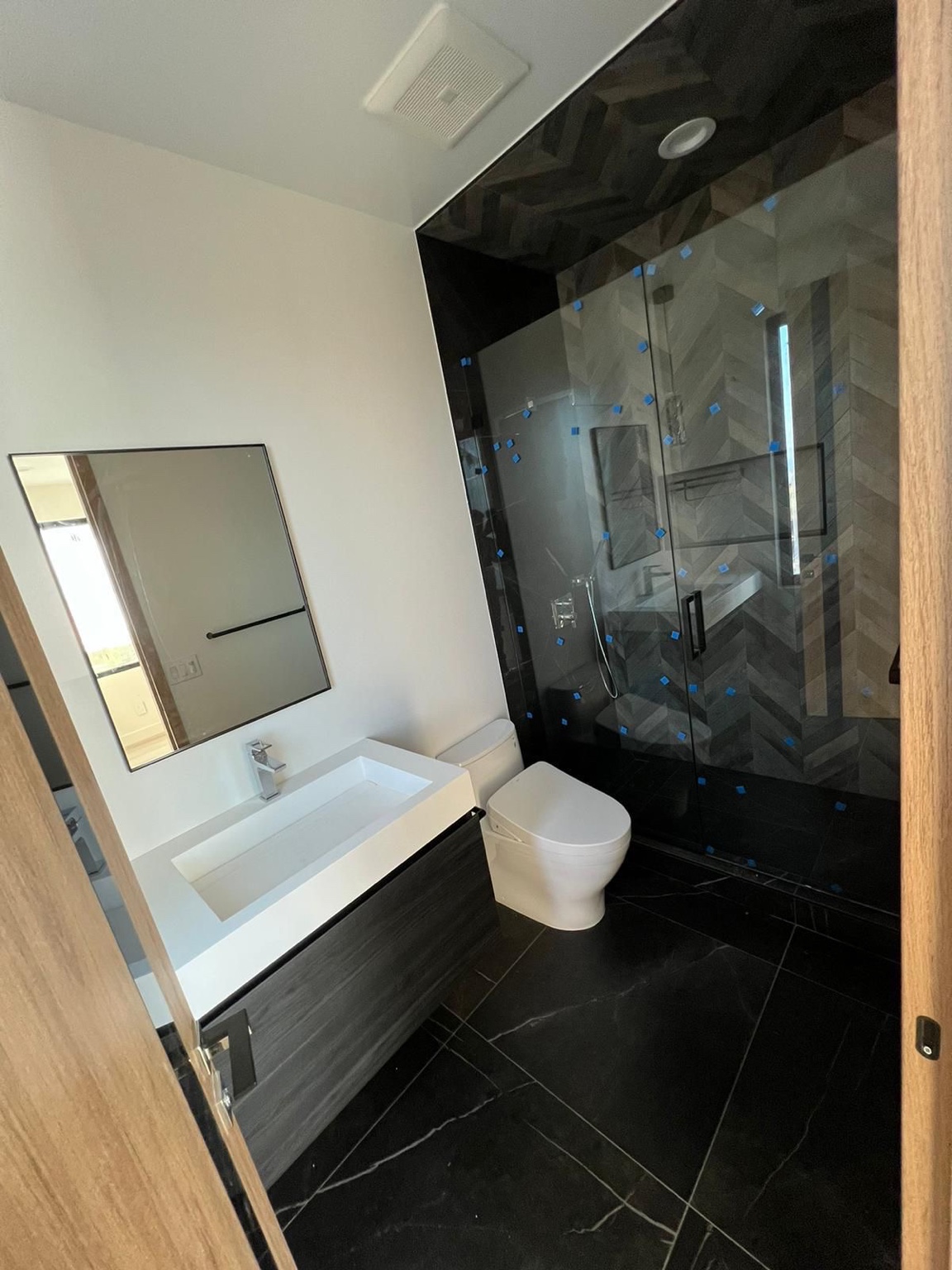 Bathroom in progress with dark tile, glass shower and floating vanity