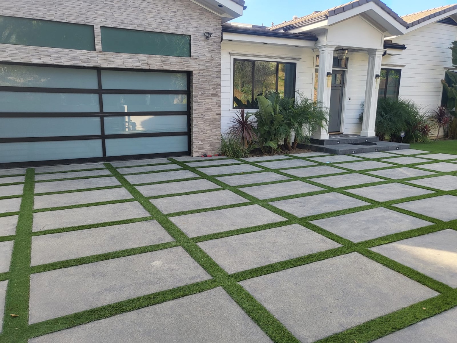 Driveway with large concrete panels and green strips in front of a modern home